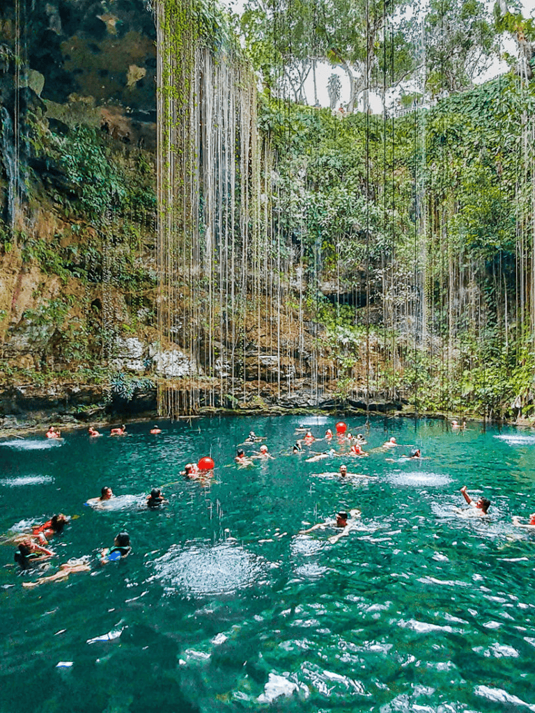 Crystal clear cenote with waterfalls, perfect for swimming and adventure activities.