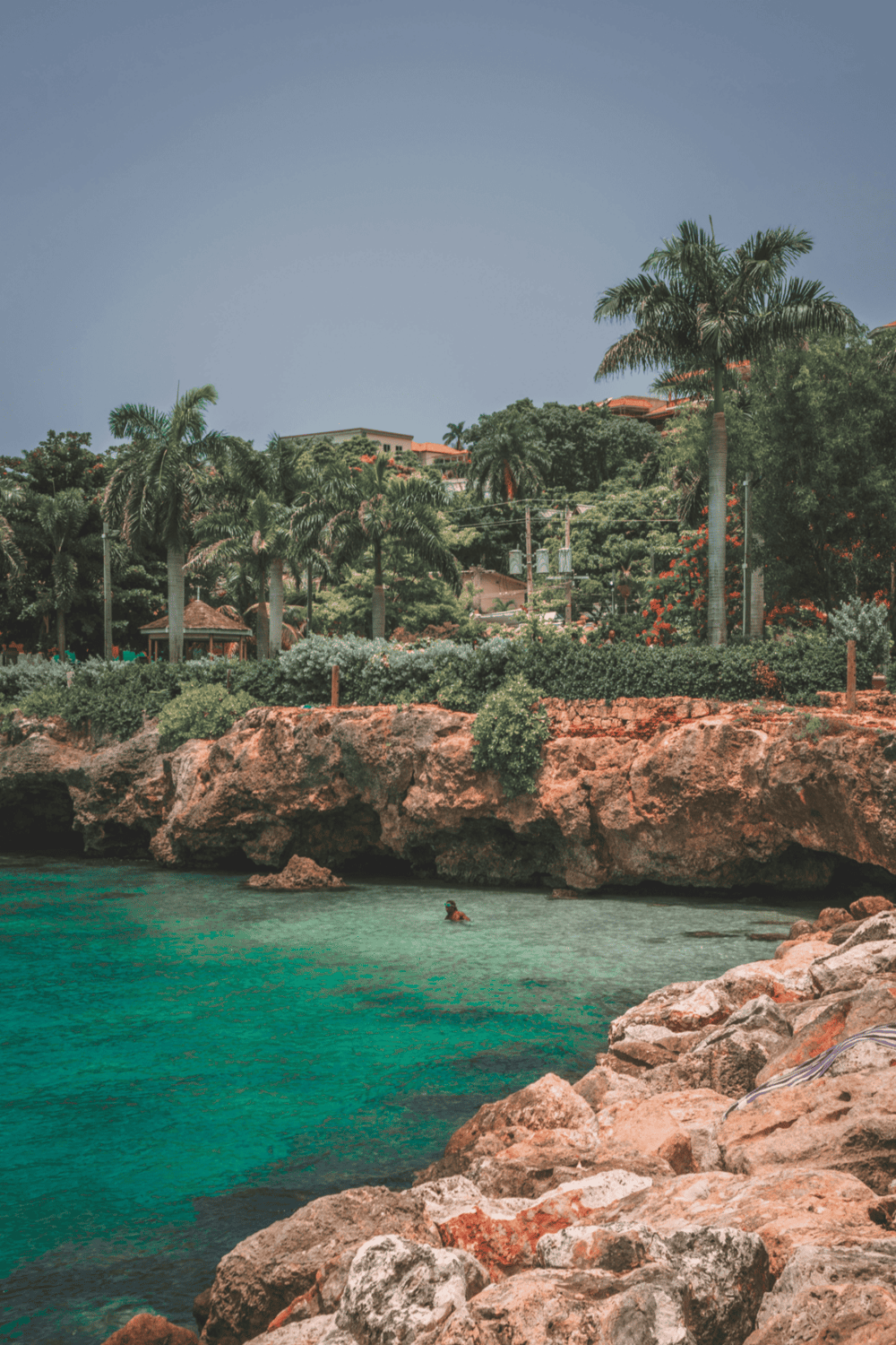 Tropical coastal landscape with lush greenery, palm trees, and clear turquoise waters perfect for travel exploration.