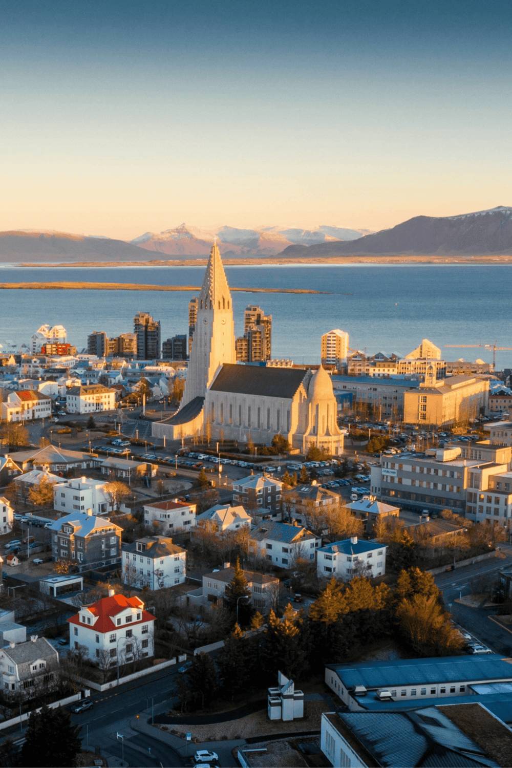 Aerial view of Reykjavik, Iceland with Hallgrímskirkja church, mountains, and water at sunset.