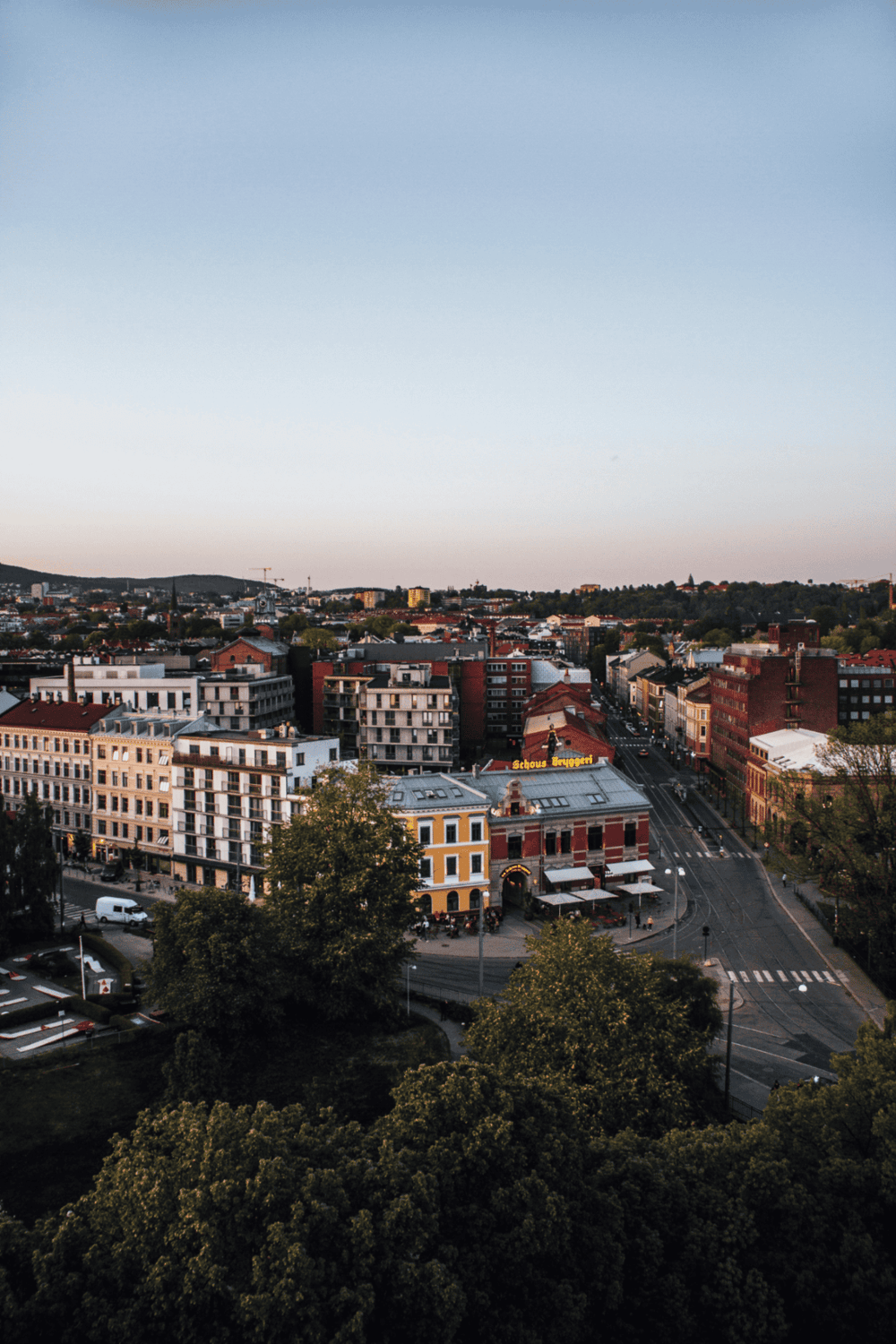 Aerial view of a cityscape with historic buildings and green trees at sunset - QuestForDirections.