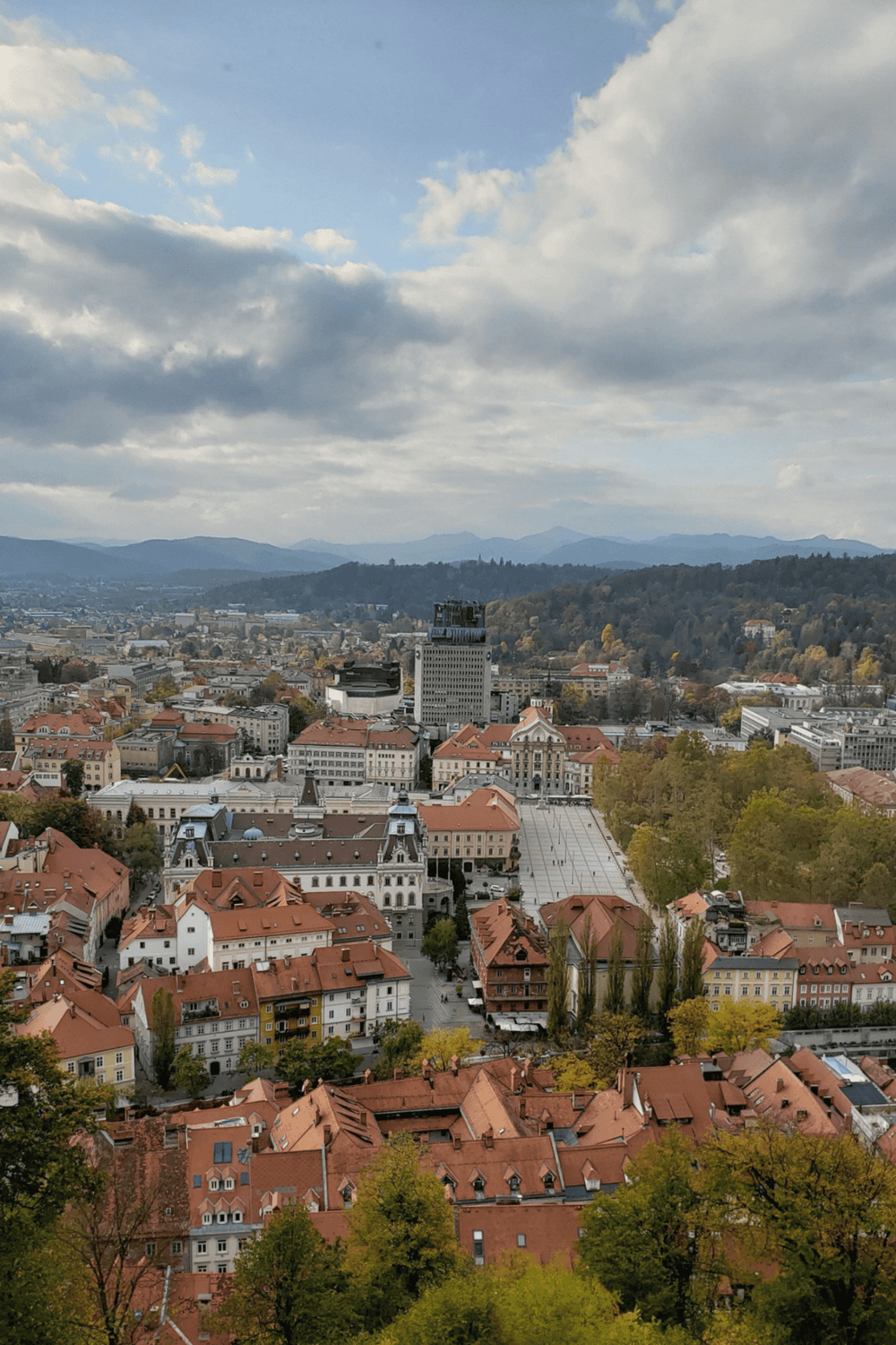 Panoramic view of Ljubljana city with historic architecture and surrounding hills, captured from a high vantage point.