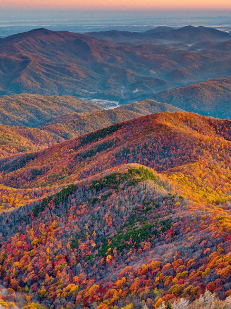 Vast fall foliage landscape of lush mountain ridges with colorful trees during autumn.
