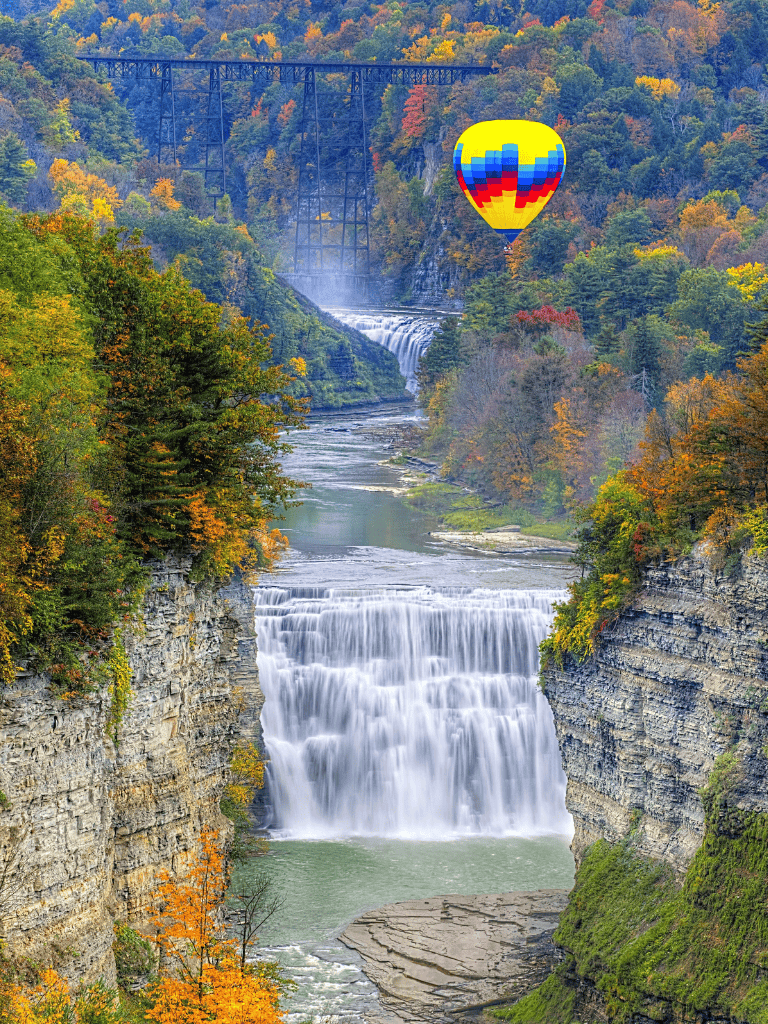 Colorful hot air balloon flying over autumn waterfall landscape at Cuyahoga Valley National Park.
