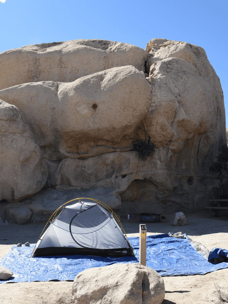 Airstream tent setup with boulders and clear sky at outdoor camping site.