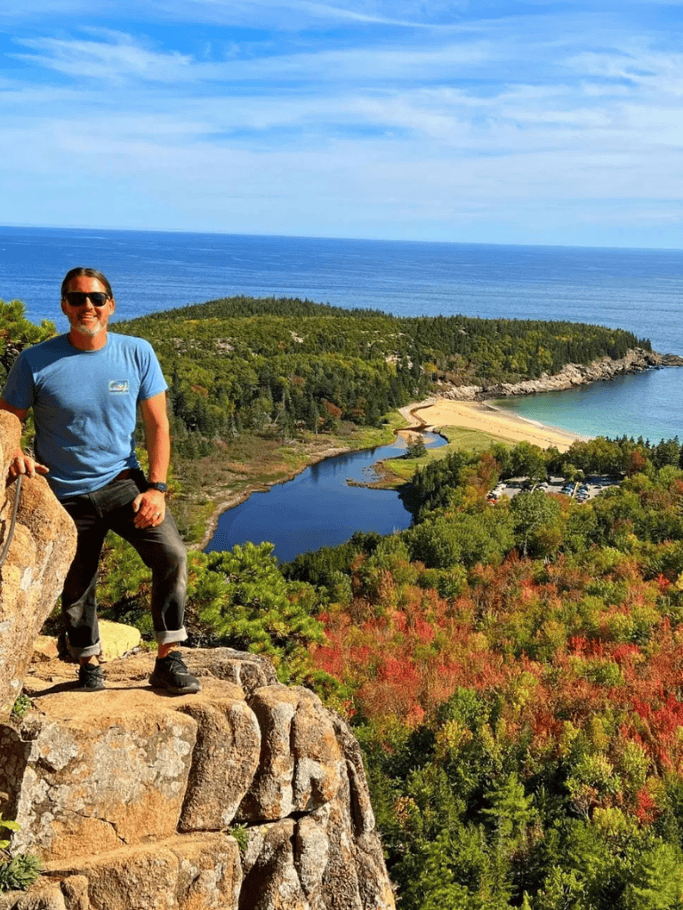 Stunning coastal view with hiker overlooking lush landscape and ocean backdrop.