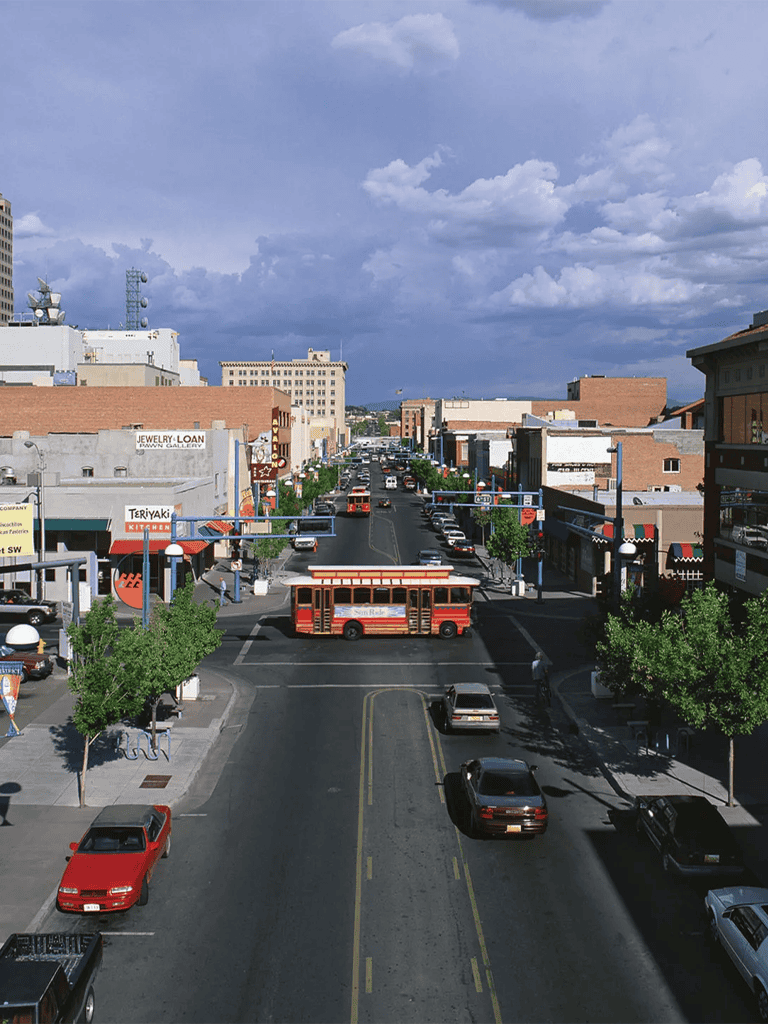Downtown city street with trolley, shops, and vehicles, vibrant urban scene for travel planning.