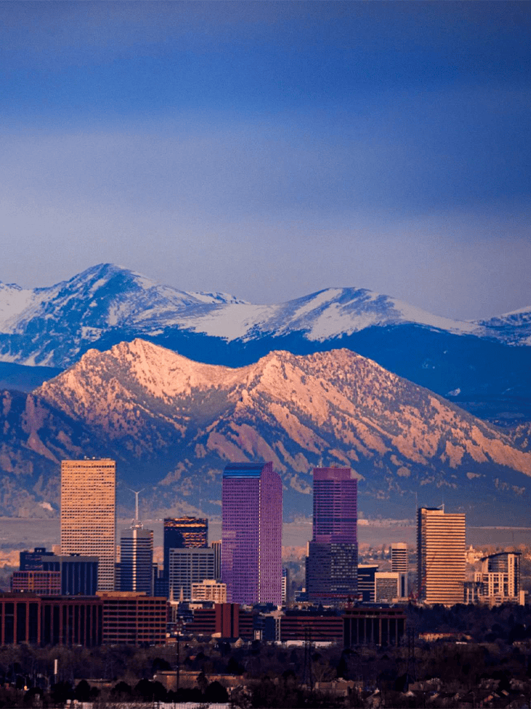 Snow-capped mountains behind Los Angeles downtown skyline, California, scenic cityscape and mountain view.