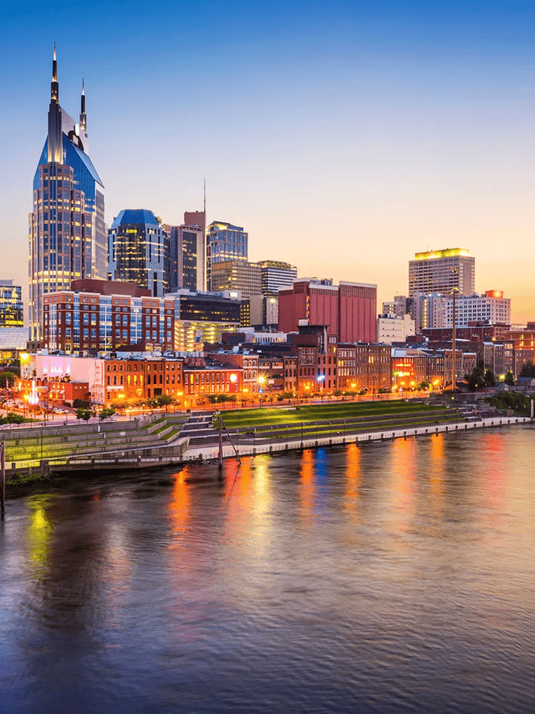 Bright Nashville skyline with skyscrapers and river at sunset.
