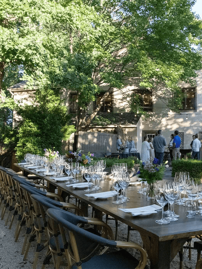 Elegant outdoor wedding reception setup with glassware and floral centerpieces, surrounded by lush greenery.