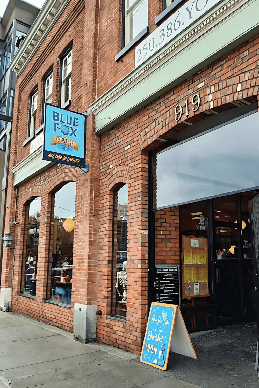 Bright blue Blue Fox Cafe sign on brick building, popular local breakfast spot, inviting outdoor dining area, downtown location.