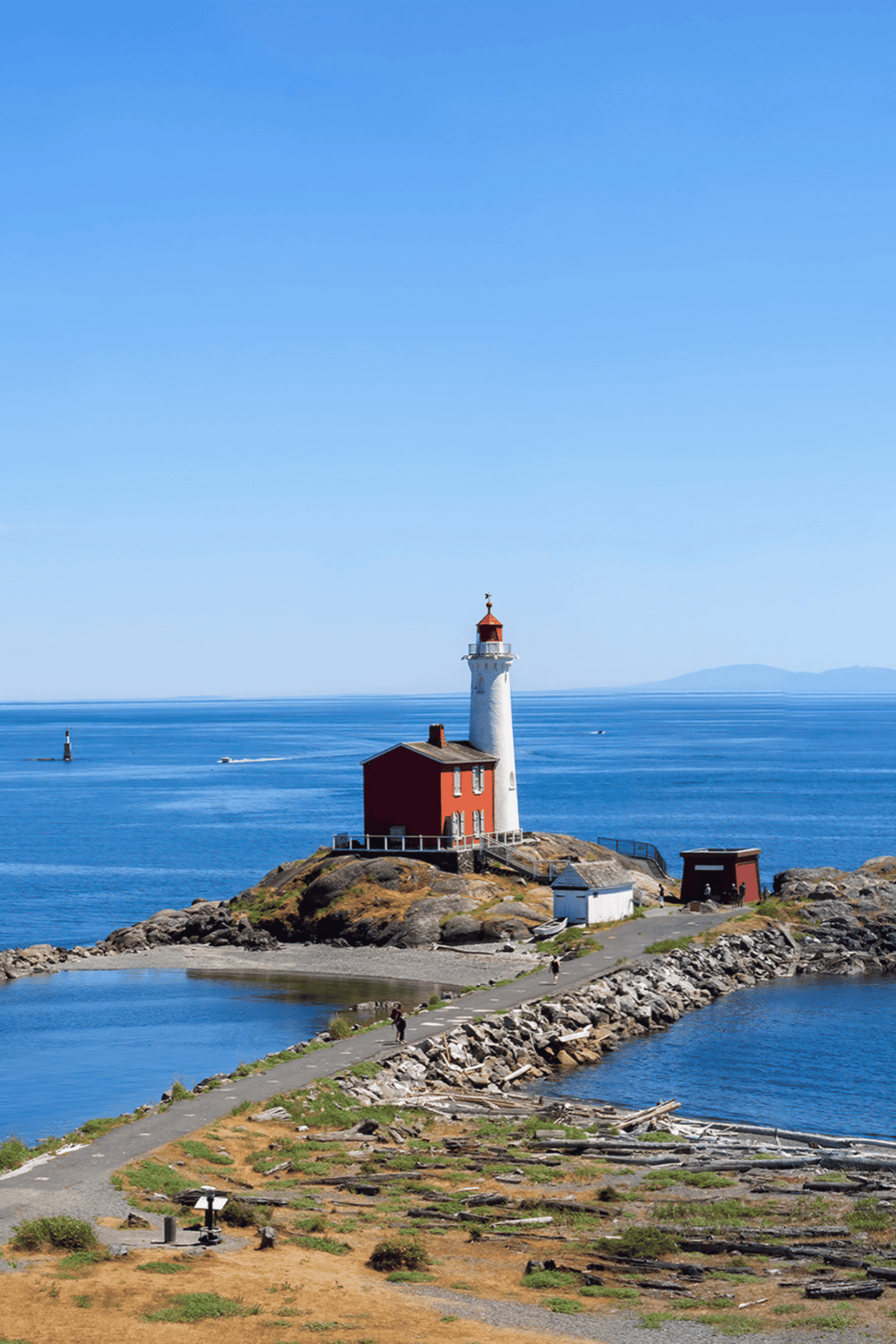 Lighthouse on rocky coast, scenic ocean view, Pacific Northwest, vessel in water.