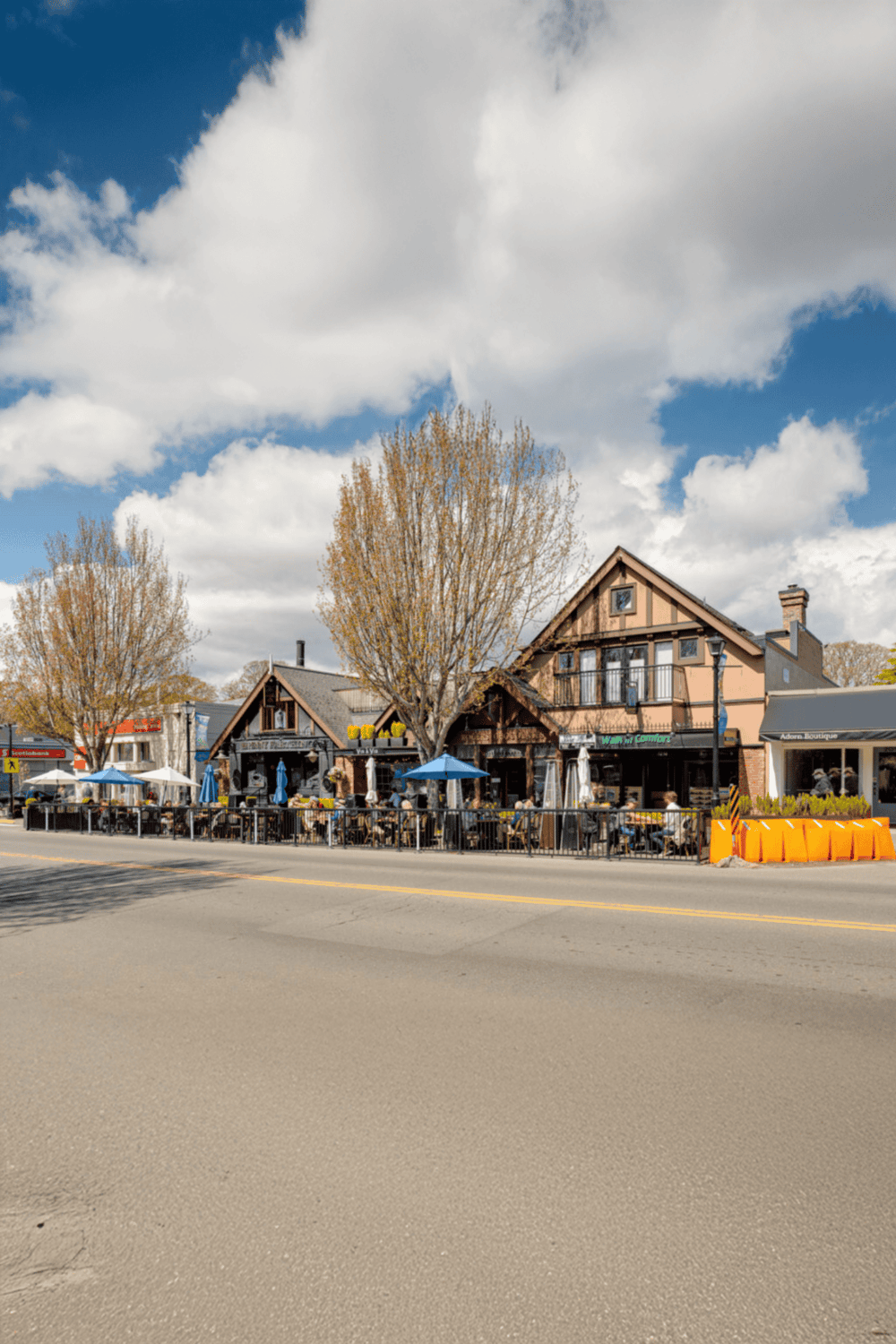 Cozy downtown restaurant with outdoor seating and colorful umbrellas under a blue sky.