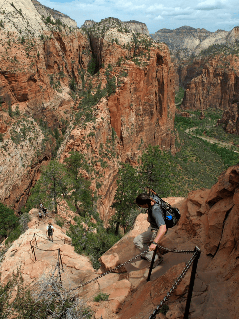 Spectacular view of Zion Canyon with hikers descending a narrow, chain-lined trail in Zion National Park.