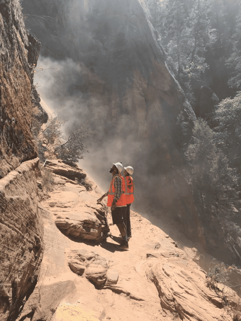 Climber rescue on rugged canyon trail with smoke and steep cliffs in Zion National Park.