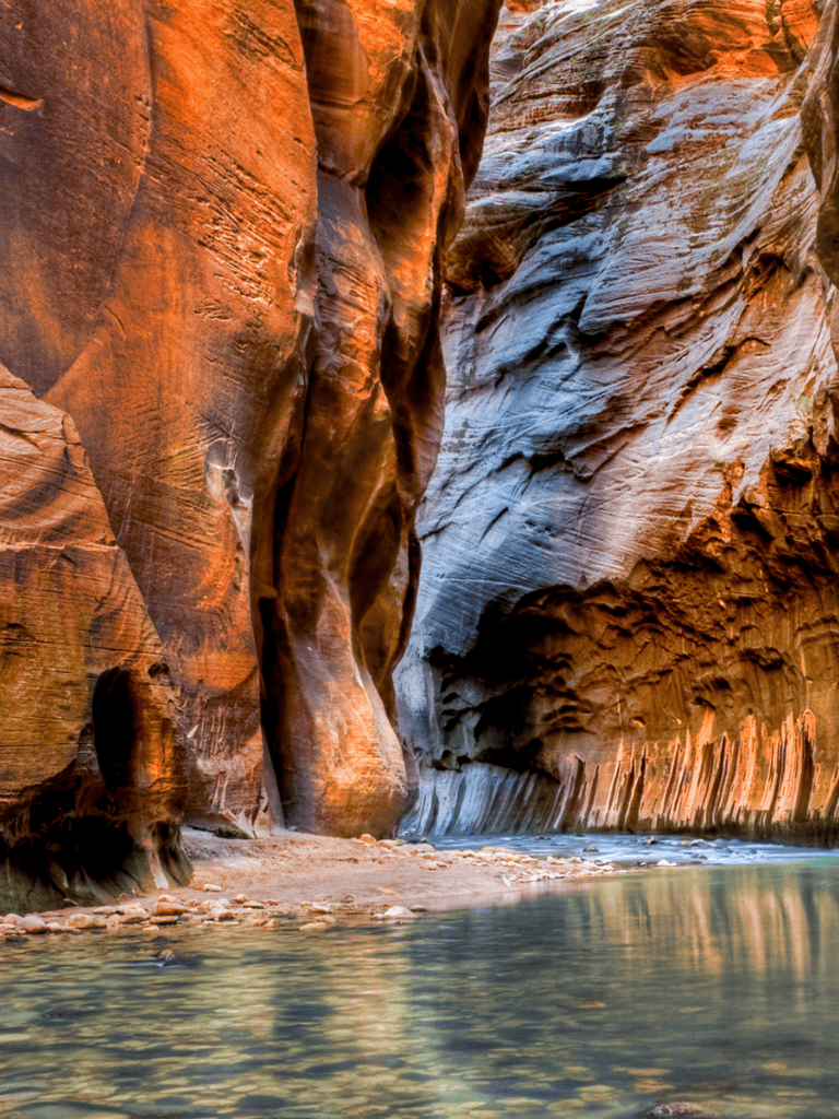 Vivid canyon walls with a tranquil river in a slot canyon, stunning natural landscape.