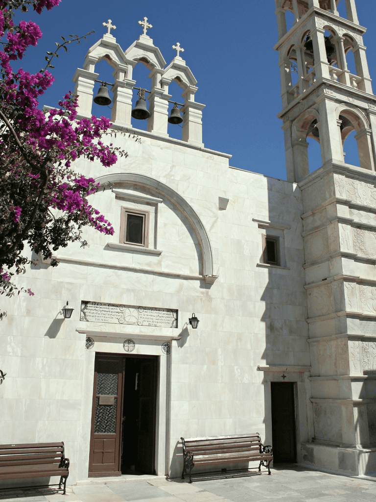 Ancient church with white stone construction and bell tower under clear blue sky.