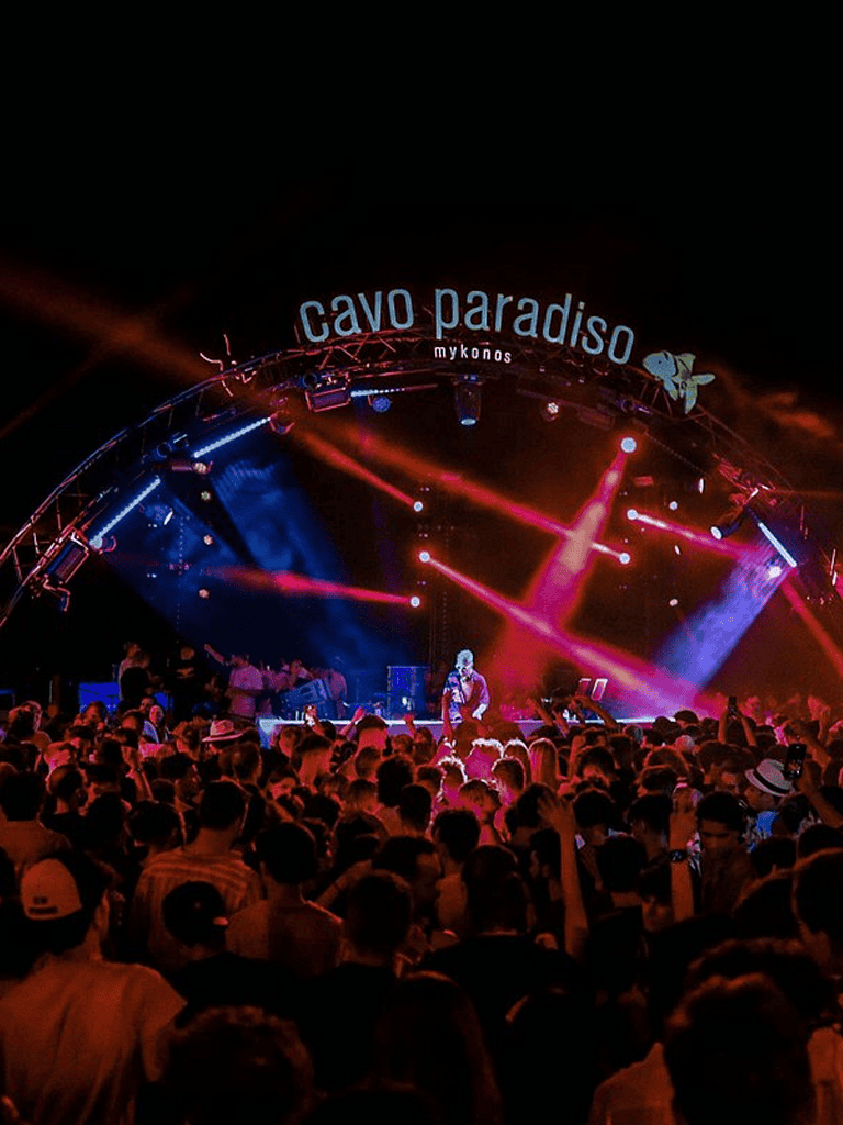 Vibrant night concert at Cavo Paradiso Mykonos with colorful stage lights and lively crowd, a top destination for music lovers.