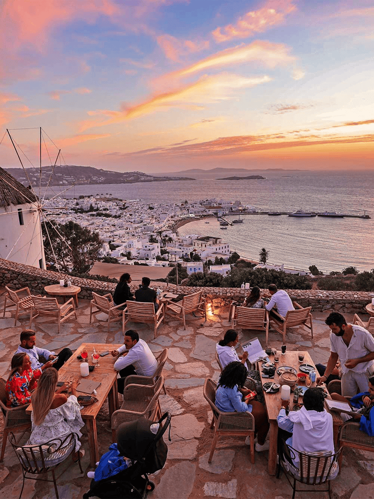 Breathtaking sunset view over a seaside restaurant dining scene in Greece.