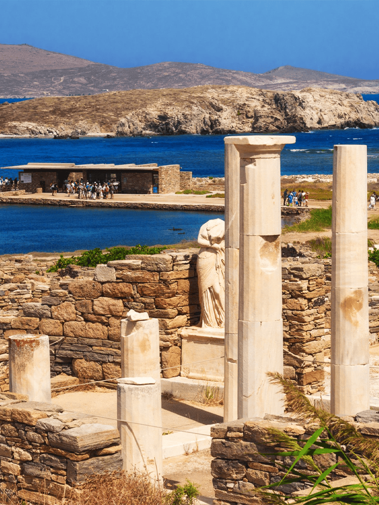 Ancient Greek ruins on the coastline with stone columns and scenic ocean view in the background.