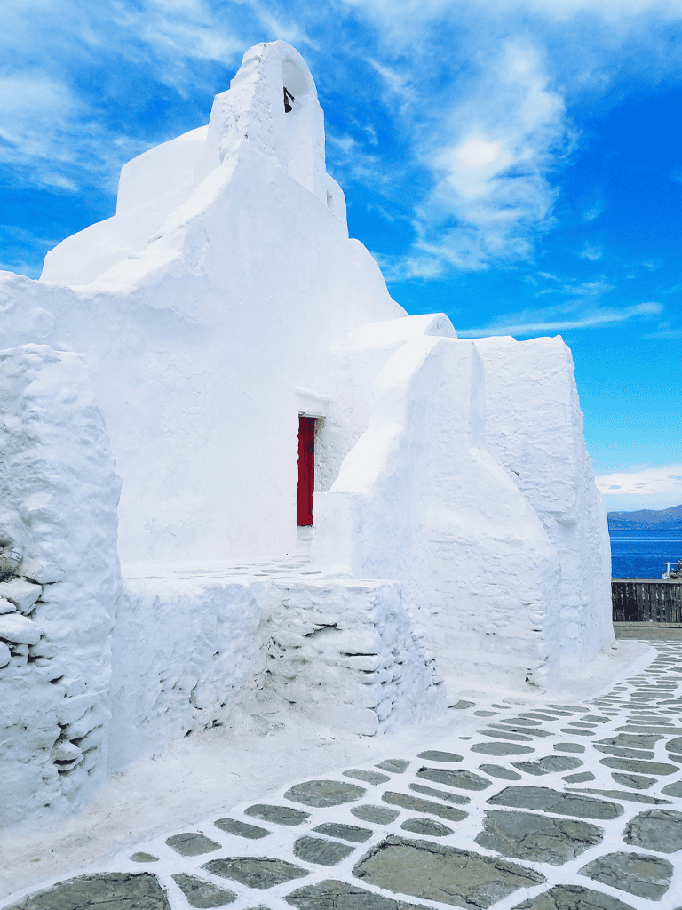 White Greek church with red door in Santorini, Greece.