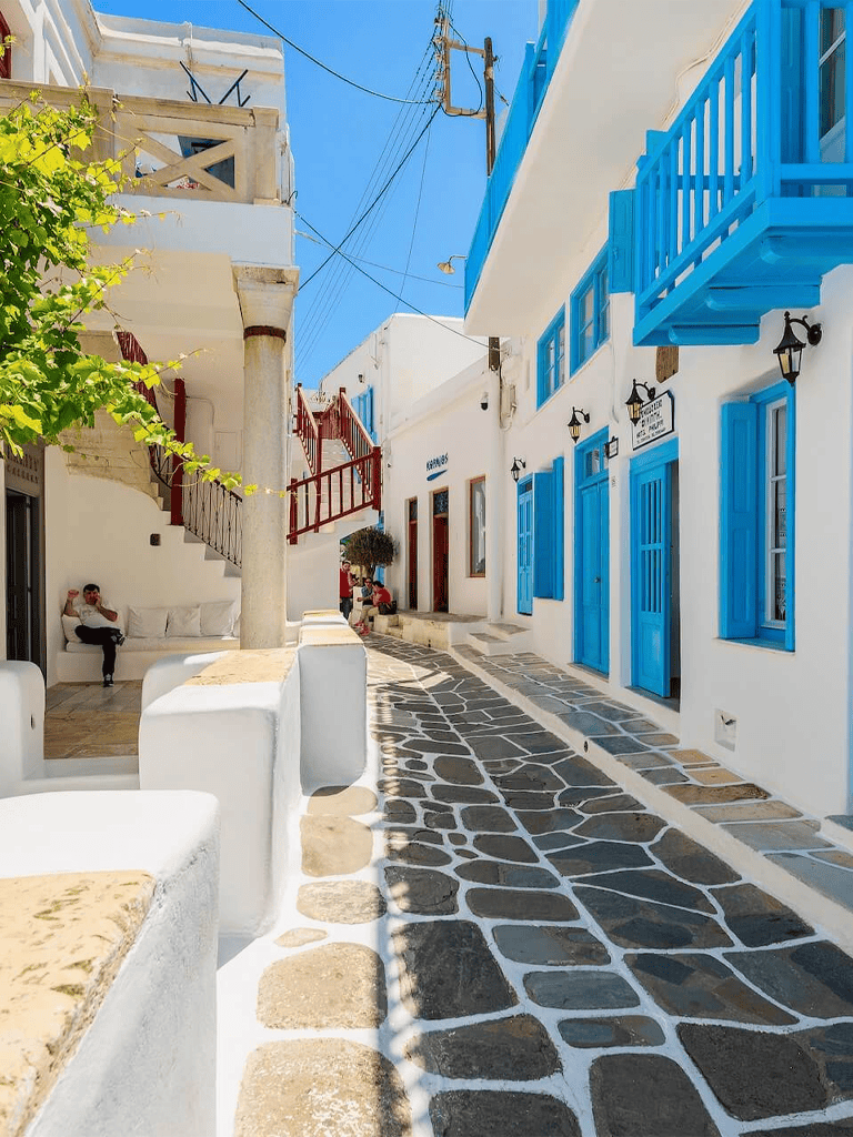 - Bright white buildings with vibrant blue accents in a picturesque Greek island street.
