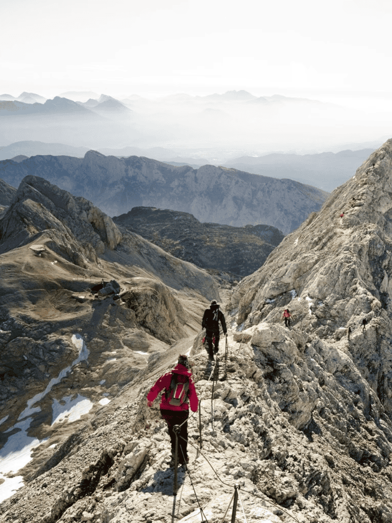 1. High-altitude mountain climbers ascending rugged terrain with safety ropes and backpacks.
