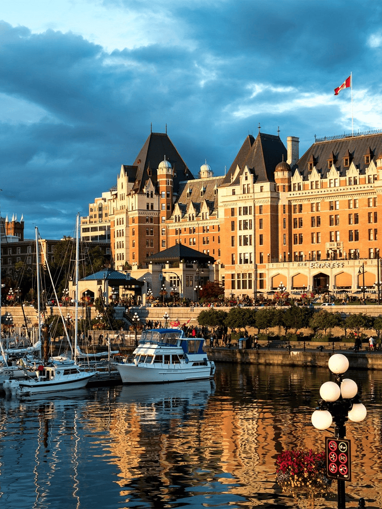 Luxurious hotel on waterfront with sailing boats and historic architecture, perfect for travel planning.