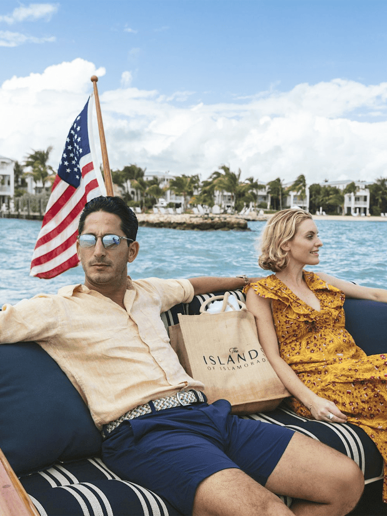 Relaxed couple enjoying boat ride in the Florida Keys with island views and American flag, exploring Isla Americana destinations.