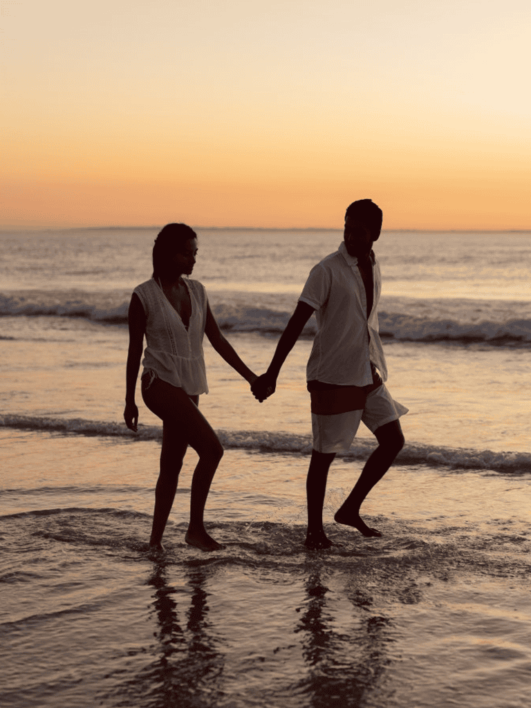 Silhouettes of a couple walking hand in hand on a beach at sunset, romantic seaside moments, perfect for travel and vacation photos.