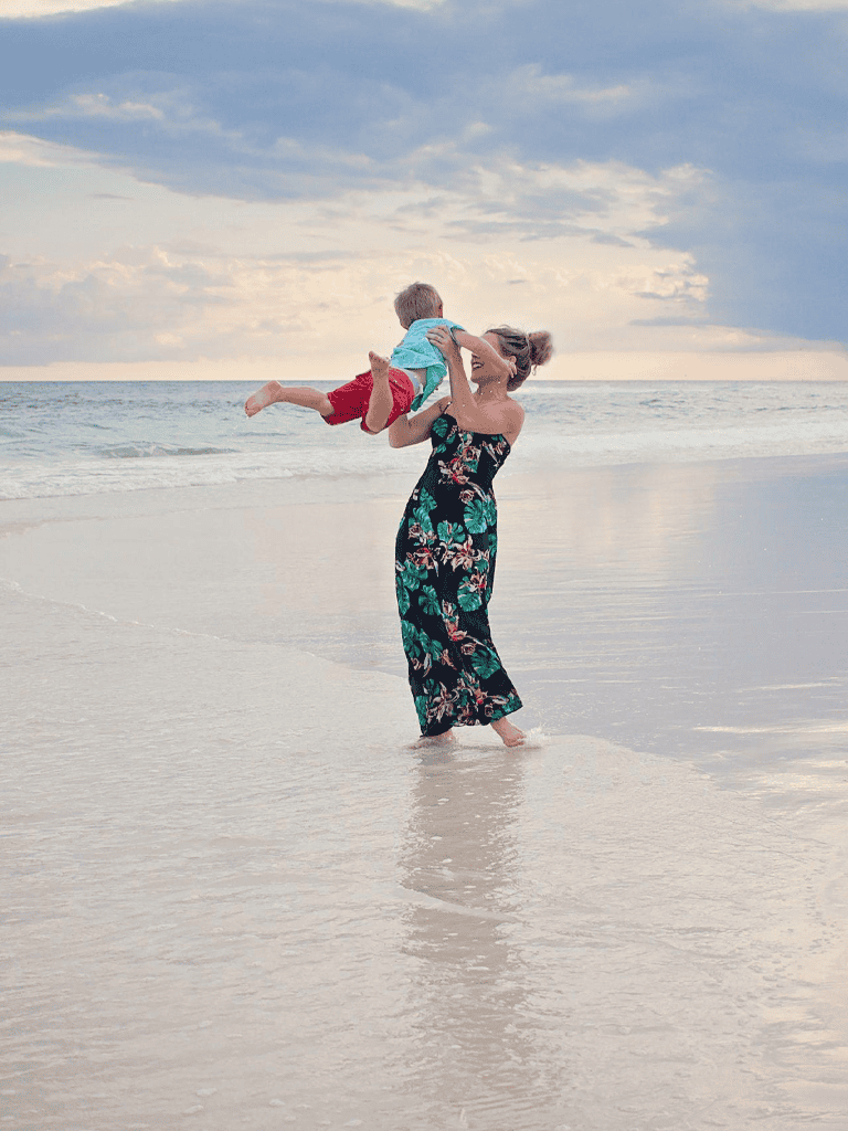 1. Mother and child playing on beach with ocean view for travel directions and family vacation planning.