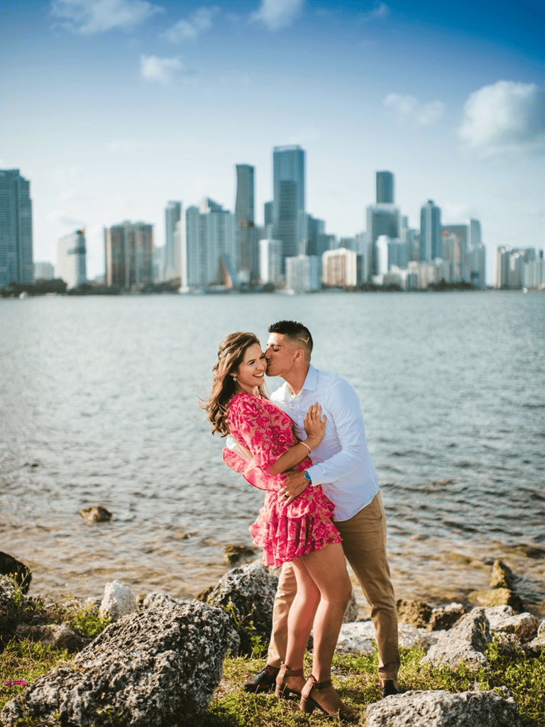 Romantic couple kiss on city waterfront, skyscraper skyline in background, romantic date at the park.
