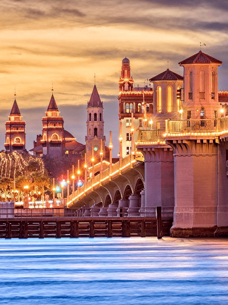 Charming Parisian-style castle illuminated at dusk by the water with string lights and architectural details.