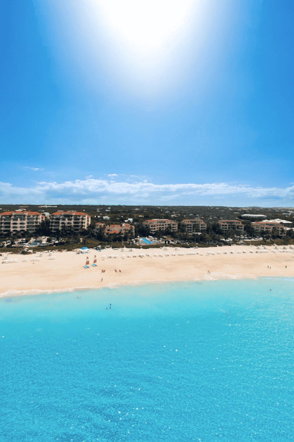 Beach resort with turquoise waters, sunlit sky, and beachfront hotels for vacation travelers.