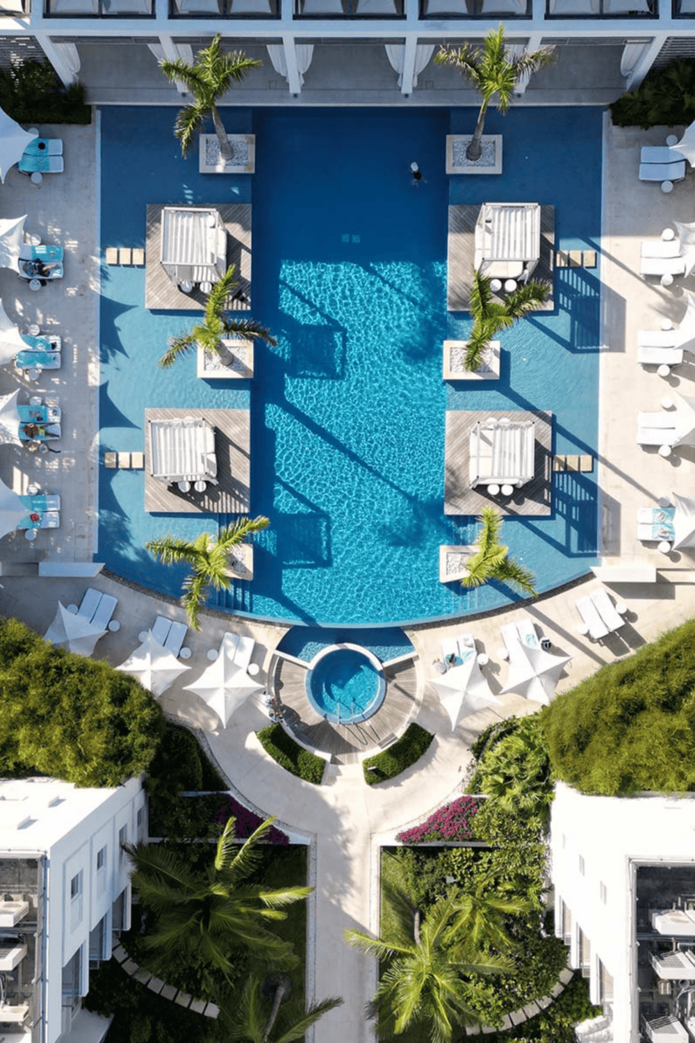 Luxury hotel pool with cabanas and palm trees, tropical resort scene, outdoor swimming pool area with sun loungers and umbrellas in vacation destination.
