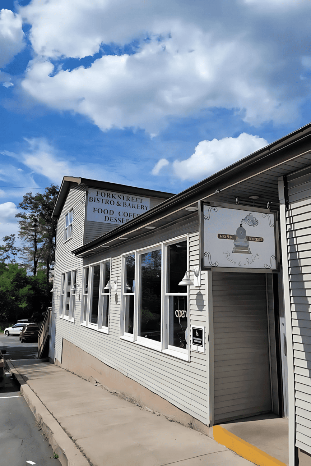 1. Cozy bakery and cafe with white siding, large windows, and outdoor seating under a blue sky.