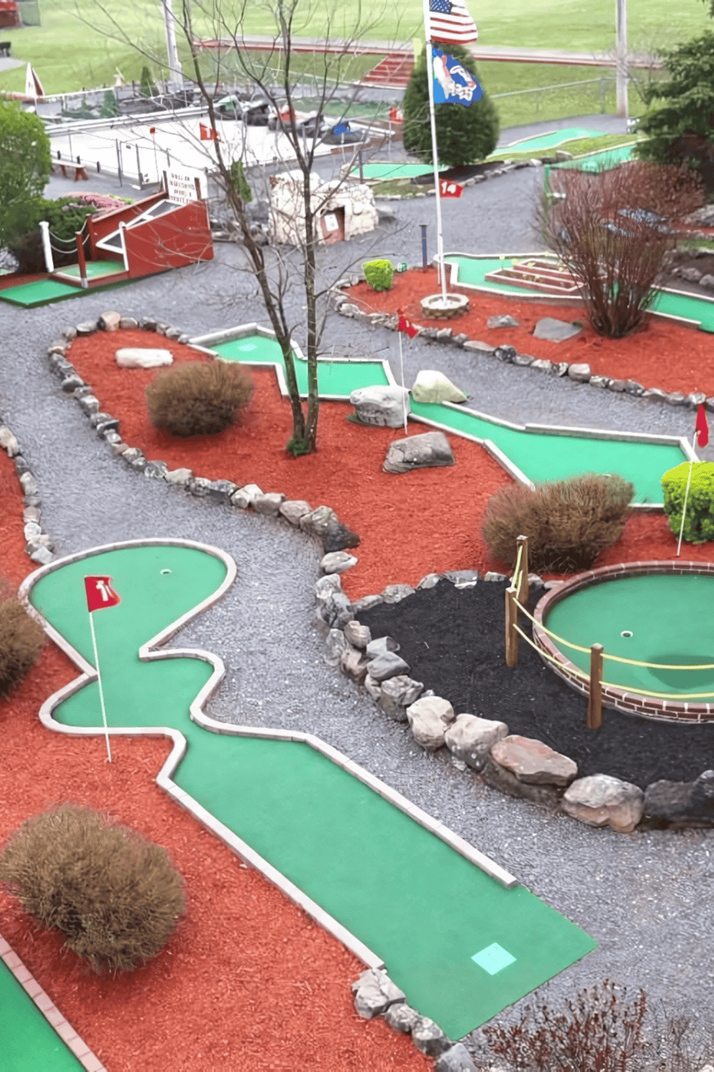 Miniature golf course with multiple holes, flags, and landscaped surroundings, perfect for family fun and entertainment.