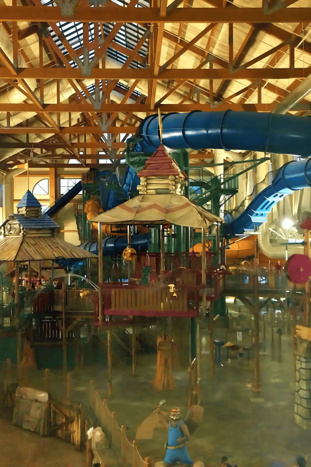 Indoor water park with large water slides and wooden themed structures for family fun.