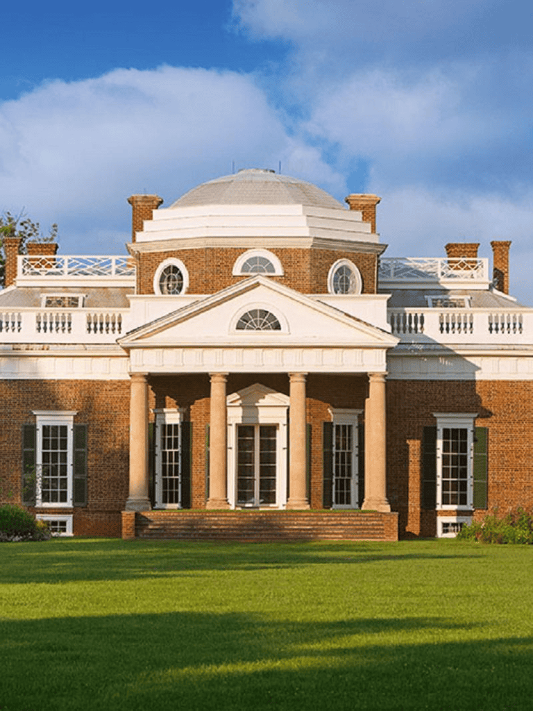 Elegant historic mansion with classical architecture and lush green grounds.