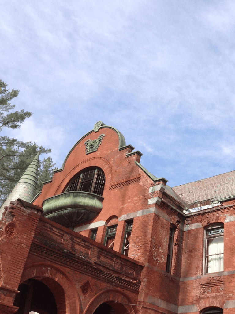 Old brick architectural building with a curved window and decorative elements.