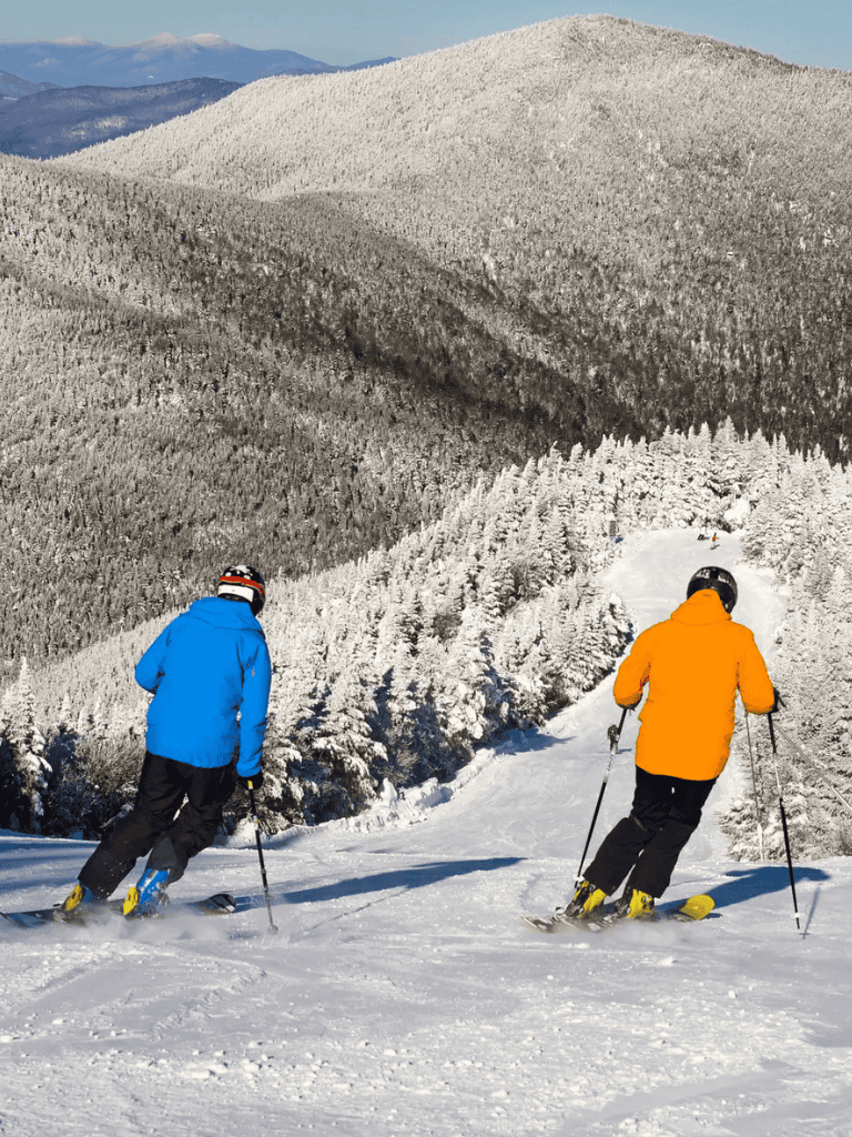 Snow-covered mountain landscape with skiers in colorful jackets enjoying winter sports.