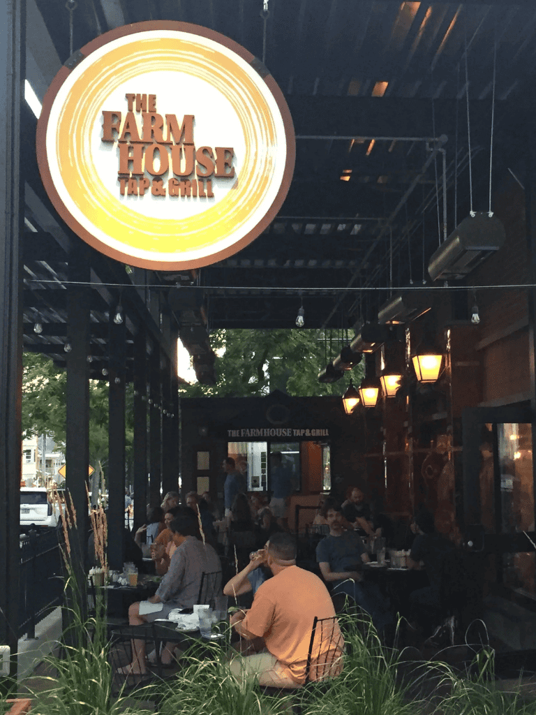 Farmhouse Tap & Grill outdoor dining area with customers, cozy ambiance, and warm lighting.