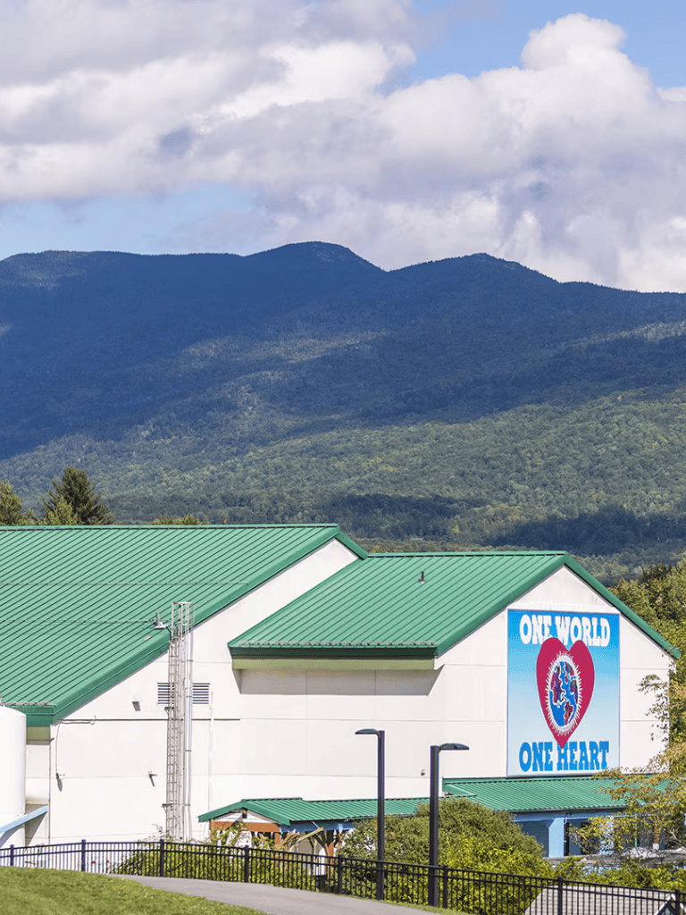 Peaceful mountain background with Quest for Directions facility featuring one world, one heart mural under sunny skies.