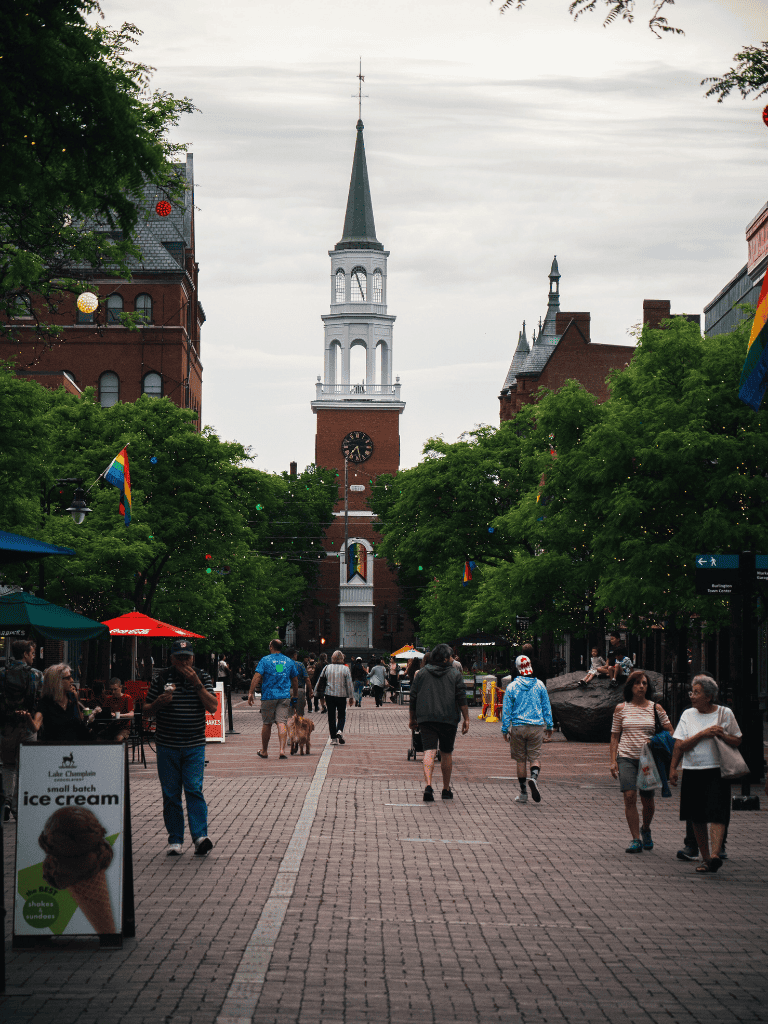 Historic downtown street with church steeple, shops, and pedestrians in the evening.
