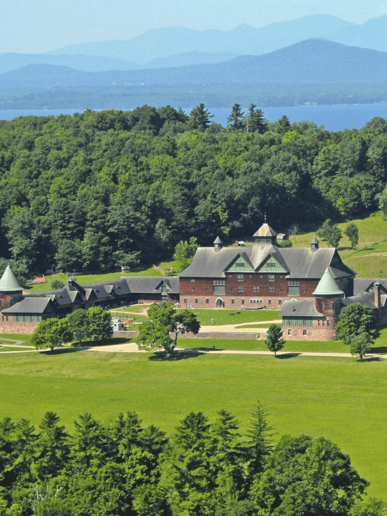 Secluded historic castle surrounded by lush green forest with scenic mountain views in the background.