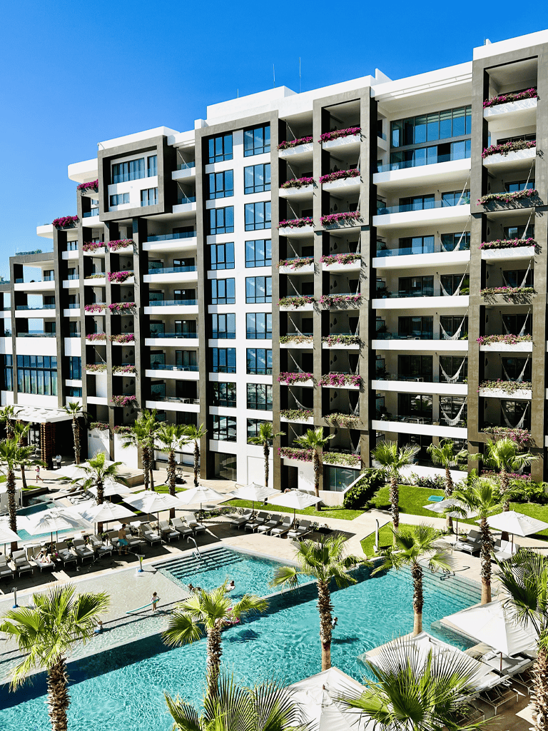 Luxurious modern hotel with pool, palm trees, and city views, perfect for vacation stays.