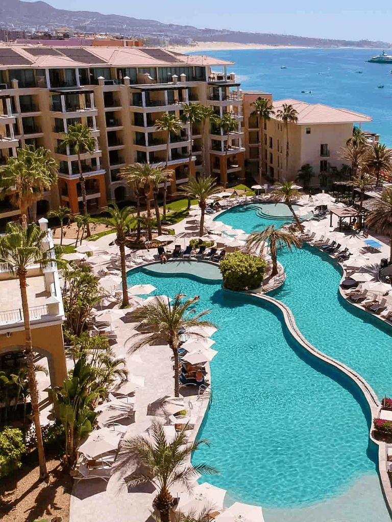 Luxurious beach resort swimming pool with palm trees and ocean view, perfect for relaxation and leisure.