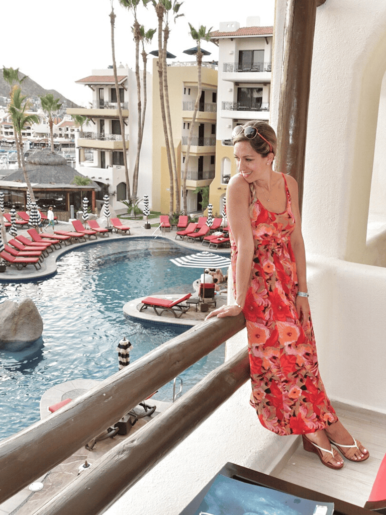 Sunny woman in floral sundress overlooking hotel pool at QuestForDirections resort.