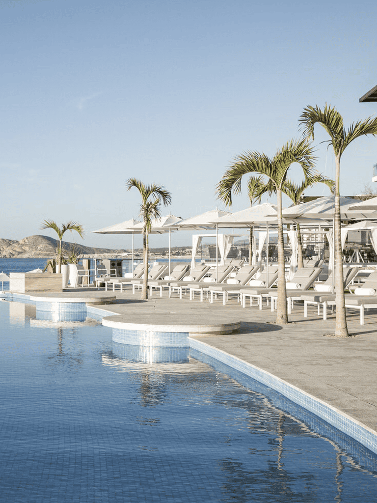 Luxurious poolside resort with cabanas, palm trees, and ocean view experience.