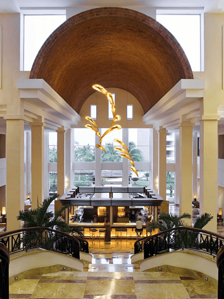 Luxurious hotel lobby with high arched ceiling, modern chandelier, and spacious design.