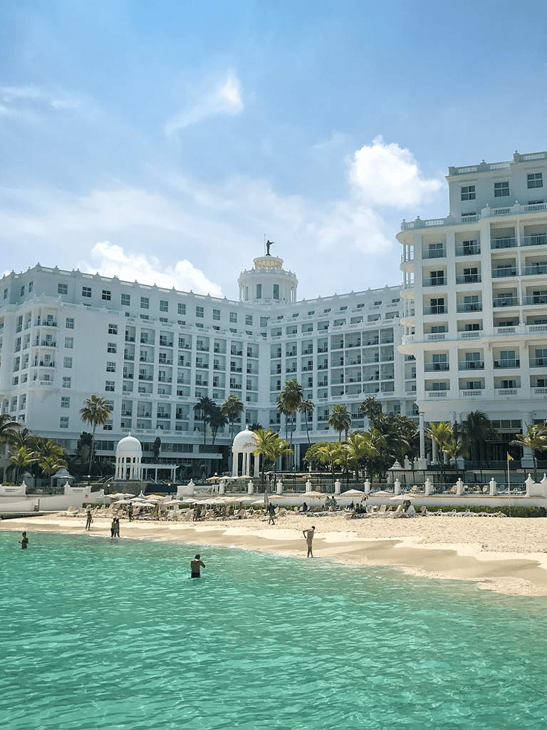 Luxurious beach resort with ocean views, white hotel building, and palm trees. Perfect for vacation or relaxation.